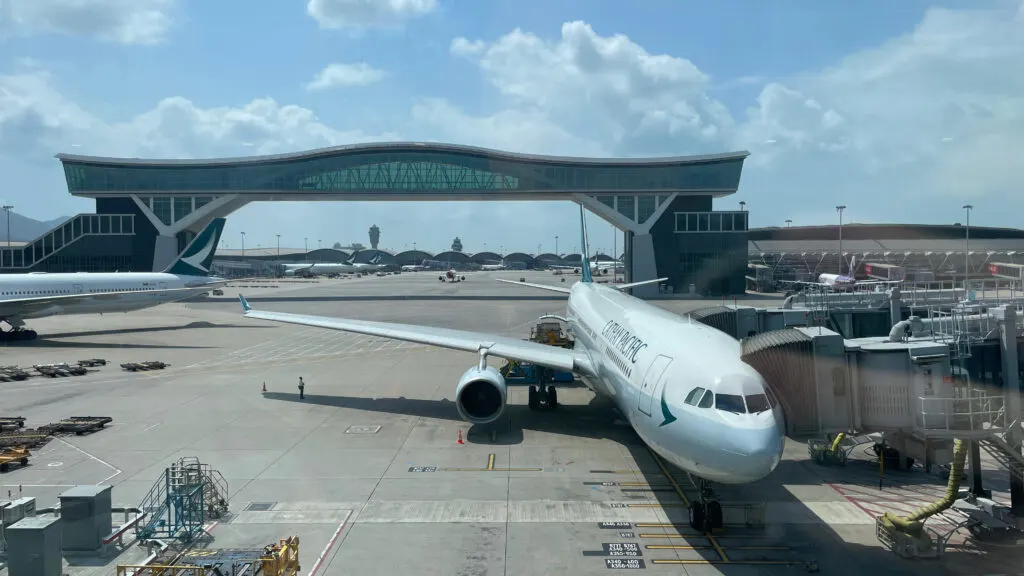 Cathay Pacific A330 parked at Hong Kong International Airport with the Sky Bridge to the Satellite Terminal in the background.
